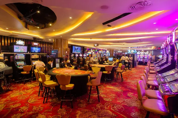 Uma jovem relaxando com o celular enquanto elementos dinâmicos de cassino flutuam ao seu redor, ilustrando a experiência móvel fluida oferecida pelo app 5YYY.